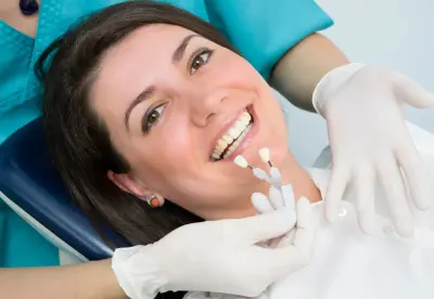 A woman is smiling while getting her teeth checked.