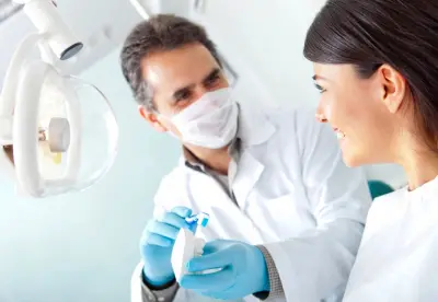 A dentist and his assistant are smiling for the camera.