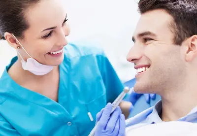 A dentist and his assistant are smiling at each other.